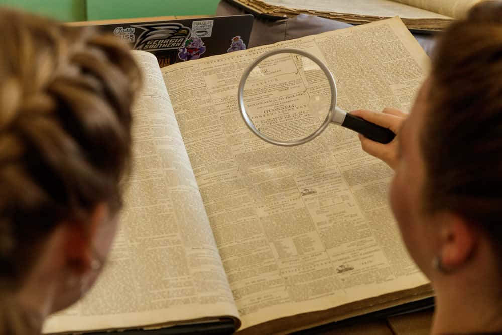 students using a magnifying glass to read a historic text